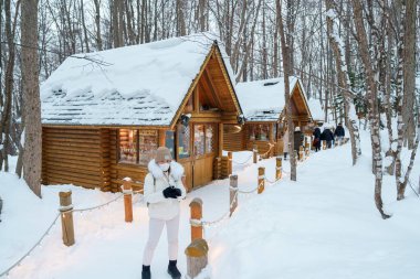 Furano 'yu ziyaret eden kadın turist, kazaklı gezgin kışın Snow' la Ningle Terrace Cottages 'ı gezen gezgin. Japonya 'nın Hokkaido şehrinde önemli ve popüler bir yer. Seyahat ve Tatil kavramı