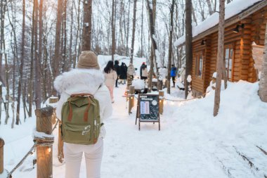 Furano 'yu ziyaret eden kadın turist, kazaklı gezgin kışın Snow' la Ningle Terrace Cottages 'ı gezen gezgin. Japonya 'nın Hokkaido şehrinde önemli ve popüler bir yer. Seyahat ve Tatil kavramı