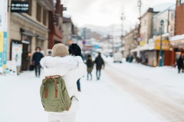 Otaru 'da kadın turist, süveter içinde mutlu bir gezgin kış mevsiminde Otaru şehrini geziyor. Japonya 'nın Hokkaido şehrinde önemli ve popüler bir yer. Seyahat ve Tatil kavramı