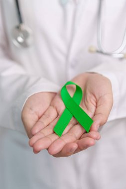 Dünya Akıl Sağlığı Günü için yeşil kurdeleli doktor, karaciğer, safra kesesi, safra kesesi, rahim ağzı, böbrek kanseri ve lenfoma farkındalığı ayı. Sağlık ve dünya kanser günü konsepti