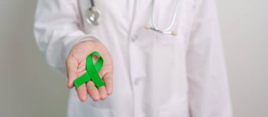 Dünya Akıl Sağlığı Günü için yeşil kurdeleli doktor, karaciğer, safra kesesi, safra kesesi, rahim ağzı, böbrek kanseri ve lenfoma farkındalığı ayı. Sağlık ve dünya kanser günü konsepti