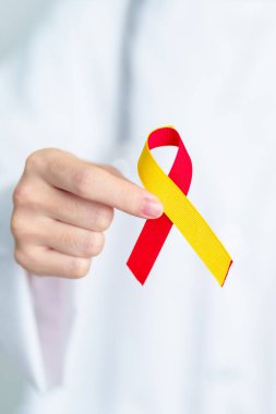 Doktor kırmızı ve sarı kurdele tutuyor. Dünya Hepatit Günü Farkındalık Ayı, 28 Temmuz, Karaciğer kanseri, Sarılık, Siroz, Başarısızlık, Büyümüş, Hepatik Ensefalopati ve Sağlık Konsepti