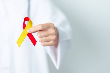 Doktor kırmızı ve sarı kurdele tutuyor. Dünya Hepatit Günü Farkındalık Ayı, 28 Temmuz, Karaciğer kanseri, Sarılık, Siroz, Başarısızlık, Büyümüş, Hepatik Ensefalopati ve Sağlık Konsepti