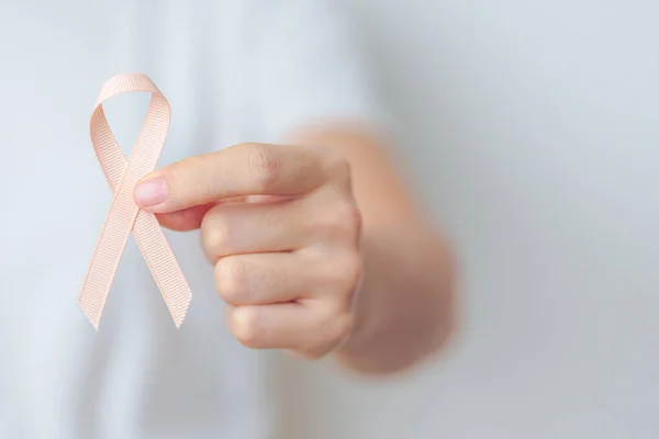 woman holding Peach Ribbon for September Uterine Cancer Awareness month. Uterus and Ovaries, Endometriosis, Hysterectomy, Uterine fibroids, Reproductive, Healthcare and World cancer day concept