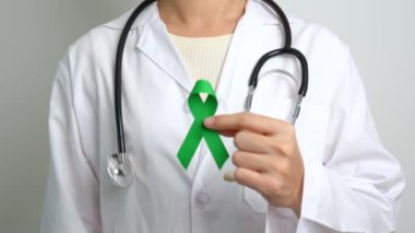 Dünya Akıl Sağlığı Günü için yeşil kurdeleli doktor, karaciğer, safra kesesi, safra kesesi, rahim ağzı, böbrek kanseri ve lenfoma farkındalığı ayı. Sağlık ve dünya kanser günü konsepti