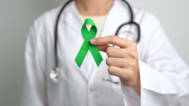 Dünya Akıl Sağlığı Günü için yeşil kurdeleli doktor, karaciğer, safra kesesi, safra kesesi, rahim ağzı, böbrek kanseri ve lenfoma farkındalığı ayı. Sağlık ve dünya kanser günü konsepti