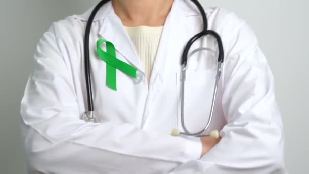 世界精神保健デーのための緑のリボンを持つ医師 子宮頸がんやリンパ腫意識月 医療と世界のがんの日のコンセプト — ストック動画