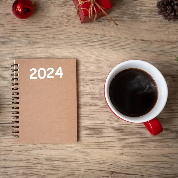 2024ノート ブラックコーヒーカップ 木製テーブル トップビュー コピースペースのクリスマスギフト Xmas ハッピーニューイヤー 解決策 リストを行うには 戦略と計画コンセプト — ストック写真