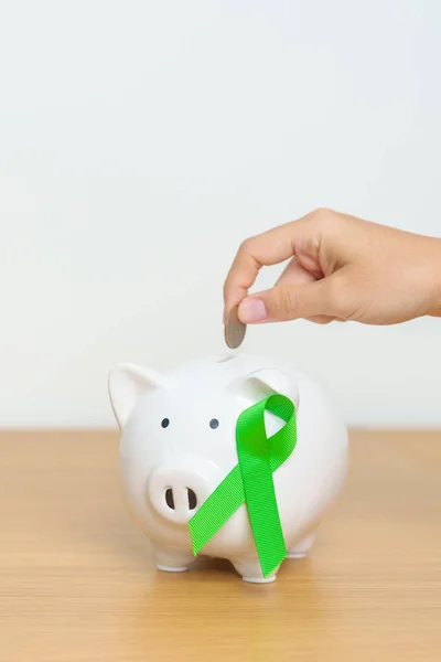Liver, Gallbladders, bile duct, cervical, kidney Cancer and Lymphoma Awareness month, green Ribbon with Piggy Bank for support illness life. Health, Donation, Charity, Campaign, Money Saving, Fund