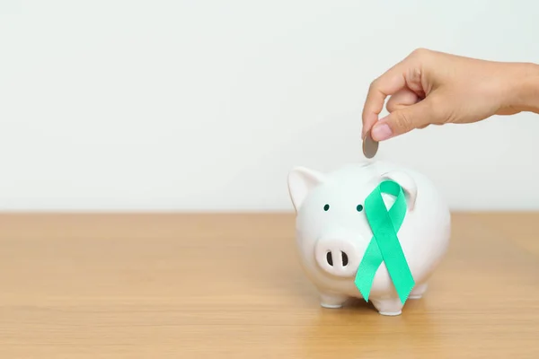 September Ovarian cancer Awareness month, Teal Ribbon with Piggy Bank for support illness life. Health, Donation, Charity, Campaign, Money Saving, Fund and World cancer day concept
