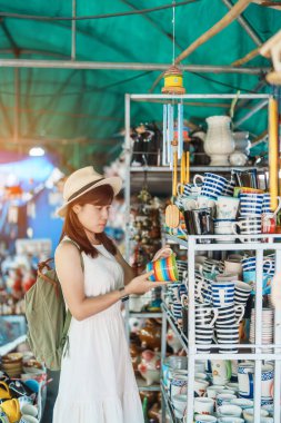 Genç Asyalı kadın gezgin elinde kupa turistler için seramik dükkanında, kız ziyaretinde Lampang, Tayland