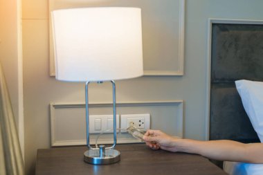 Modern yatak odasındaki en küçük lambayı açan ya da kapatan kadın eli. Daire yaşam konsepti