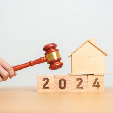 Emlak Hukuku, Ev Sigortası, Emlak Vergisi, Açık Artırma ve Açık Artırma Konsepti. 2024 yıllık blok, mahkeme masasında tokmak adalet çekici olan küçük oyuncak ev modeli..