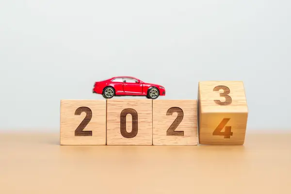 2023 flipping to 2024 year block with car model on table. Automobile Tax, Car Insurance, Financial, vehicle Repair and Maintenance and New Year concept