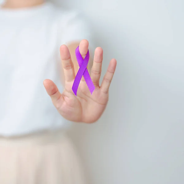 Woman holding purple Ribbon for Violence, Pancreatic, Esophageal, Testicular cancer, Alzheimer, epilepsy, lupus, Sarcoidosis and Fibromyalgia. Awareness month and World cancer day concept
