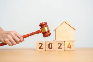 Emlak Hukuku, Ev Sigortası, Emlak Vergisi, Açık Artırma ve Açık Artırma Konsepti. 2024 yıllık blok, mahkeme masasında tokmak adalet çekici olan küçük oyuncak ev modeli..