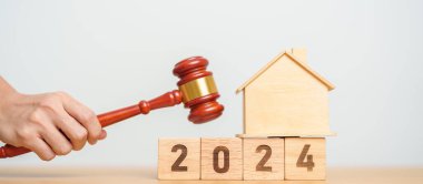 Emlak Hukuku, Ev Sigortası, Emlak Vergisi, Açık Artırma ve Açık Artırma Konsepti. 2024 yıllık blok, mahkeme masasında tokmak adalet çekici olan küçük oyuncak ev modeli..