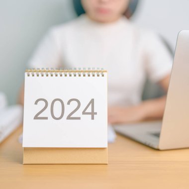 2024 Yıllık Takvim dizüstü bilgisayar kullanan bir iş kadınıyla masada. Geri sayım, Mutlu Yıllar, Çözünürlük, Hedefler, Plan, Eylem, Görev ve Mali Konsept