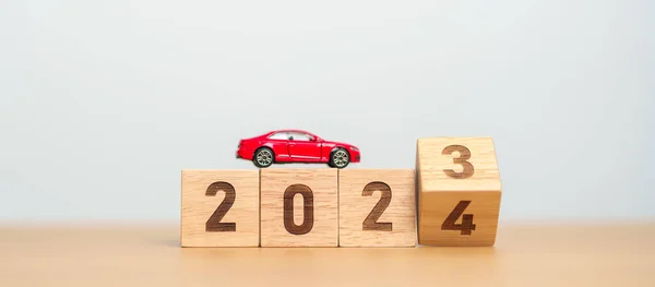 2023 flipping to 2024 year block with car model on table. Automobile Tax, Car Insurance, Financial, vehicle Repair and Maintenance and New Year concept