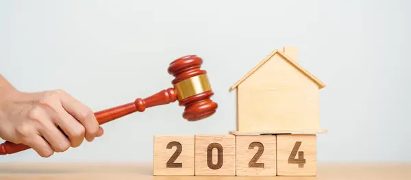 Real Estate Law, Home Insurance, property Tax, Auction and Bidding concepts. 2024 year block with small toy house model with gavel justice hammer on desk in courthouse.
