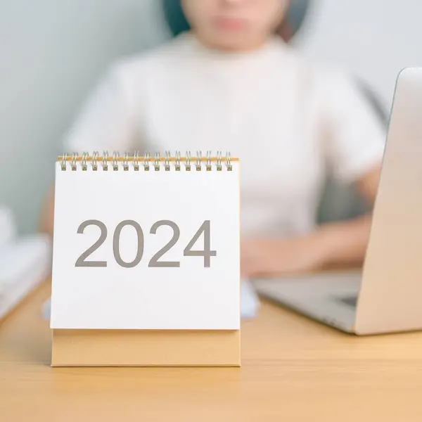 2024 Year Calendar on table with business woman using laptop computer. countdown, Happy New Year, Resolution, Goals, Plan,  Action, Mission and financial Concept