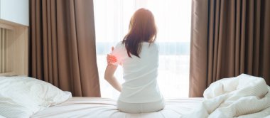 Evde yatakta yatarken kolu ağrıyan bir kadın, uyandıktan sonra kas hasarı ve ağrısı. Sağlık ve Tıp Konsepti