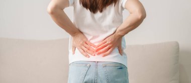 Evdeki koltukta otururken sırt ağrısı çeken bir kadın. Piriforis Sendromu, bel ağrısı ve omurga baskısı nedeniyle kas ağrısı olan yetişkin bir kadın. Ofis sendromu ve tıbbi konsept