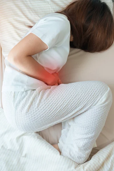 woman having abdomen ache due to Stomach pain, digestion with constipation or Diarrhea from food poisoning, female problem and Endometriosis, Hysterectomy and Menstrual on the bed at home