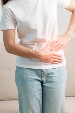 Evdeki kanepede karın ağrısı çeken bir kadın. Karaciğer kanseri, tümör, böbrek kanseri, sarılık, viral hepatit, siroz, başarısızlık, büyüme, Hepatik Ensefalopati, mide ve sağlık konsepti.