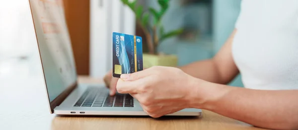 woman hand holding credit card and using laptop for online shopping while making order at home. Marketplace platform website, technology, ecommerce, digital banking and online payment concept