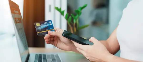 woman hand holding credit card and using laptop with mobile phone for online shopping while making order. Marketplace platform website, technology, ecommerce, digital banking and online payment