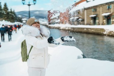 Otaru 'yu ziyaret eden kadın turist, süveter giyen mutlu gezgin kış mevsiminde Otaru kanalını geziyor. Japonya 'nın Hokkaido şehrinde önemli ve popüler bir yer. Seyahat ve Tatil kavramı