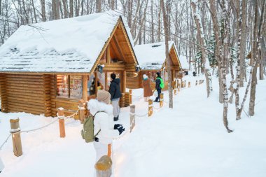 Furano 'yu ziyaret eden kadın turist, kazaklı gezgin kışın Snow' la Ningle Terrace Cottages 'ı gezen gezgin. Japonya 'nın Hokkaido şehrinde önemli ve popüler bir yer. Seyahat ve Tatil kavramı