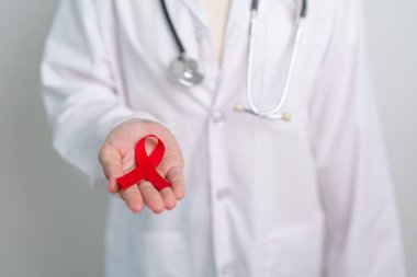 Aralık Dünya Yardım Günü için kırmızı kurdeleli doktor, bağışıklık yetmezliği sendromu, çoklu miyelom kanseri farkındalığı ayı ve Ulusal Kırmızı Kurdele haftası. Sağlık ve dünya kanser günü konsepti