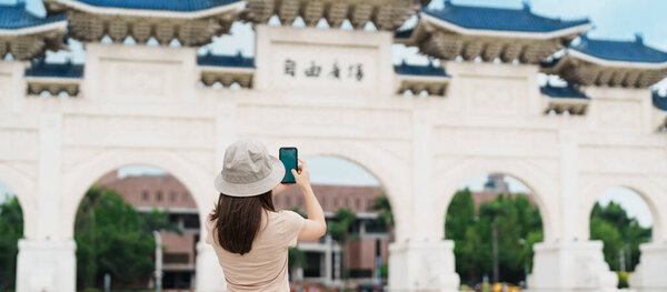 woman traveler visiting in Taiwan, Tourist taking photo and sightseeing in National Chiang Kai shek Memorial or Hall Freedom Square, Taipei City. landmark and popular attractions. Asia Travel concept