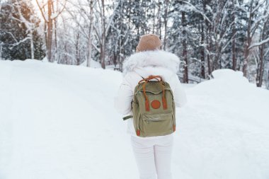 Süveter ve sırt çantalı gezgin soğuk havada karla kaplı ormanda yürüyor. Kış Seyahati, Macera, Keşif ve Tatil Konsepti