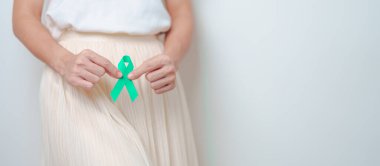 Ocak ayındaki rahim ağzı kanseri farkındalığı ayı için Teal Ribbon 'ı karnında tutan kadın. Rahim ve Yumurtalıklar, Serviks, Endometriyozis, Histektomi, Rahim fibroidleri, Üreme ve Dünya Kanser Günü Konsepti