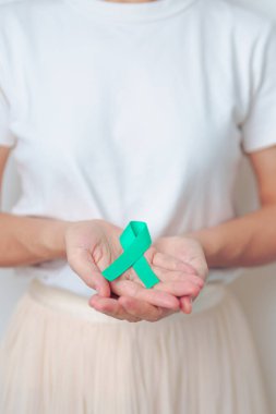 Ocak ayı boyunca Teal 'in Servikal Kanser Farkındalığı ayı için kurdele tutan kadın. Rahim ve yumurtalıklar, Rahim ağzı, Endometriyozis, Histektomi, Rahim fibroidi, Üreme, Sağlık ve Dünya Kanser Günü