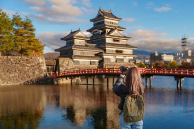 Matsumoto 'yu ziyaret eden kadın turist, Matsumoto Kalesi ya da Crow Kalesi' nde fotoğraf çeken mutlu gezgin. Matsumoto, Nagano, Japonya 'da turistler için önemli ve popüler. Seyahat ve Tatil kavramı