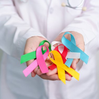 Dünya Kanser Günü, 4 Şubat. Doktor mavi, kırmızı, yeşil, beyaz, pembe, mavi ve sarı kurdeleler tutuyor. Yaşayan ve hastalıkları desteklemek için. Sağlık ve Otizm Bilinci Günü konsepti