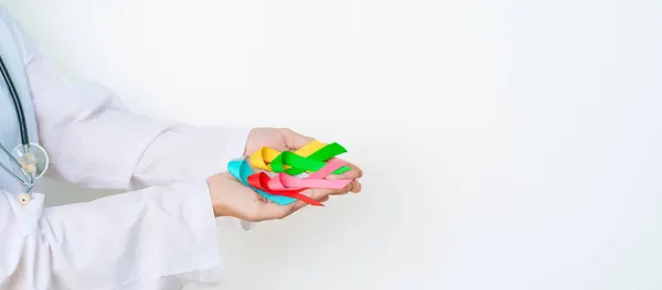 stock image World cancer day, February 4. Doctor hold colorful ribbons, blue, yellow, red, green, white, pink and grey for supporting people living and illness. Health, Medical, awareness and Insurance concept