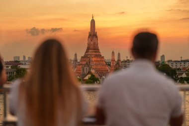 Gün batımında Wat Arun Tapınağı 'nda, Chao Phraya nehri yakınlarındaki Şafak Tapınağı manzarasının tadını çıkarırlar. Çatıdaki bardan fotoğraf çek. Bangkok, Tayland ve Güneydoğu Asya 'daki Landmark and Travel durağı