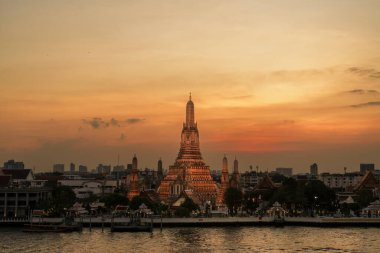 Gün batımında Wat Arun Tapınağı, Chao Phraya nehrinin yanında Şafak Tapınağı. Kent simgesi ve Bangkok, Tayland ve Güneydoğu Asya 'daki turizm ve turizm merkezleriyle ünlüdür.