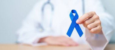 March Colectal Kanser Farkındalığı Ayı. Koyu mavi kurdeleli bir doktor. Yaşayan ve hastalıklı insanları destekliyor. Sağlık, umut ve Dünya Kanser Günü konsepti