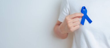 March Colectal Kanser Farkındalığı Ayı. Koyu mavi kurdeleli bir doktor. Yaşayan ve hastalıklı insanları destekliyor. Sağlık, umut ve Dünya Kanser Günü konsepti