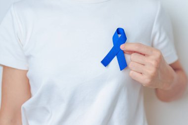 March Colectal Kanser Farkındalığı Ayı. Koyu mavi kurdeleli bir doktor. Yaşayan ve hastalıklı insanları destekliyor. Sağlık, umut ve Dünya Kanser Günü konsepti