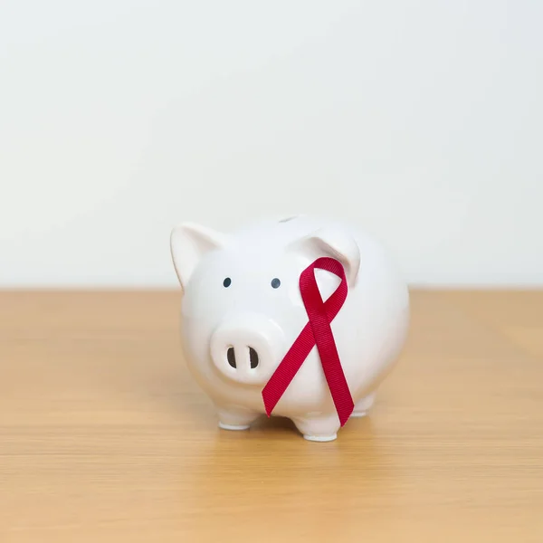December World Aids Day and multiple myeloma Cancer Awareness month, Burgundy Red  Ribbon with Piggy Bank for support illness life. Health, Donation, Charity, Campaign, Money Saving and Fund concept