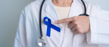 March Colectal Kanser Farkındalığı Ayı. Koyu mavi kurdeleli bir doktor. Yaşayan ve hastalıklı insanları destekliyor. Sağlık, umut ve Dünya Kanser Günü konsepti