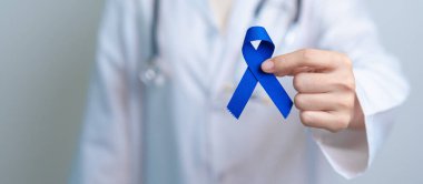 March Colectal Kanser Farkındalığı Ayı. Koyu mavi kurdeleli bir doktor. Yaşayan ve hastalıklı insanları destekliyor. Sağlık, umut ve Dünya Kanser Günü konsepti