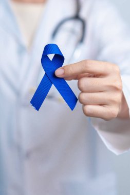March Colectal Kanser Farkındalığı Ayı. Koyu mavi kurdeleli bir doktor. Yaşayan ve hastalıklı insanları destekliyor. Sağlık, umut ve Dünya Kanser Günü konsepti